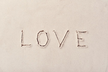 Inscription LOVE handmade on the beach sand on a sunny day