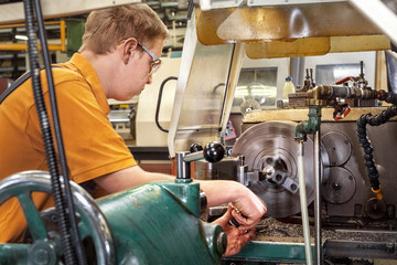A skilled worker in the metalworking industry working on a lathe