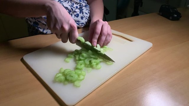 Girl slices celery on chopping the board