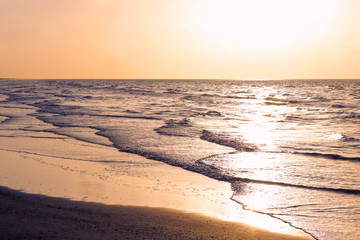 Sunrise on the beach. Gentle waves hit the shore as the sun rises over the sea. Travel and tourism...