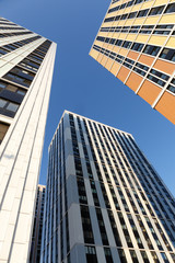 Obraz premium bottom view: construction of modern residential buildings, abstract high-rise towers with a yellow facade against a blue sky