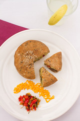 Vegetable cake with pico de gallo on white plate.