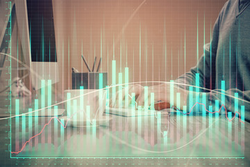 Multi exposure of graph with man typing on computer in office on background. Concept of hard work.