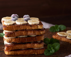 pile of square fried bread slices with chocolate and banana slices