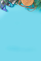 Summer vacation and travel concept. Beach accessories things - bag, hat, swimsuit, sunglasses, camera, tropical leaves on aquamarine, turquoise blue backdrop. Summer is coming trendy concept
