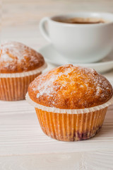 Freshly baked homemade muffins with sugar powder and a cup of coffee. Close up background