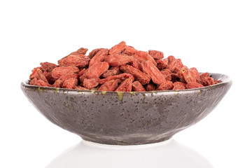 Lot of whole dried red goji in glazed bowl isolated on white background