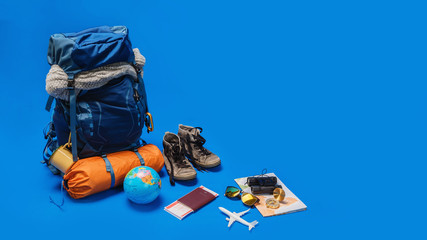 The concept of organizing equipment for traveling Put on the Luggage. concept accessory for travelers Vacation with a map,  passport on Blue color background. Travel backpack