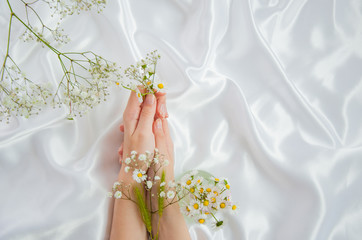 Beautiful young hands on a silk background, care using natural herbs.