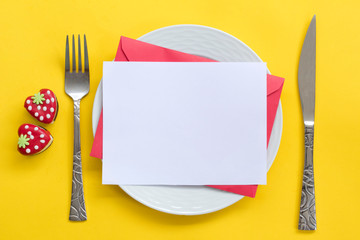 Valentine's day concept. Plate with paper card, envelope, heart-shaped cakes on yellow wooden background. 