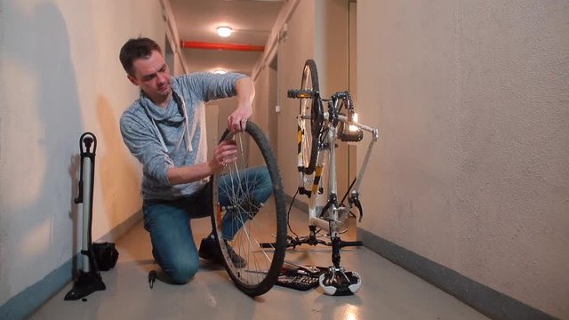 A man disassembles a bicycle wheel to seal a hole in the rubber.
