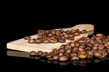 Lot of whole fresh coffee bean on wooden cutting board isolated on black glass