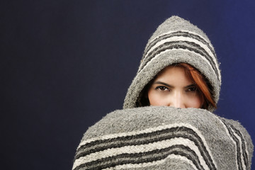 Ragazza con poncho si nasconde e mostra solo gli occhi ,  isolata su sfondo scuro