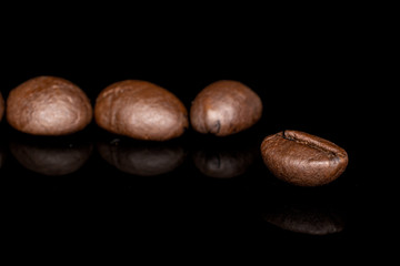 Group of four whole fresh coffee bean isolated on black glass
