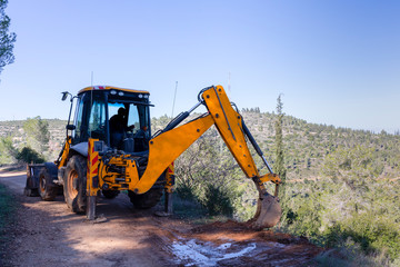 A Backhoe Loader Clearing a Muddy Path