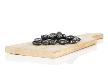 Lot of whole black bean on wooden cutting board isolated on white background
