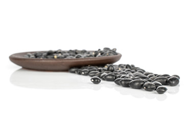 Lot of whole small black bean with brown ceramic coaster isolated on white background