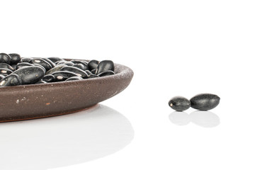 Lot of whole black bean with brown ceramic coaster isolated on white background