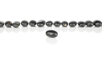 Lot of whole black bean one in focus isolated on white background