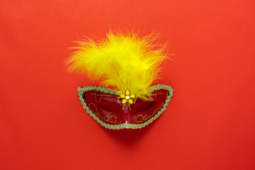 Table top view aerial image of beautiful colorful carnival festival background.Flat lay accessory object the fancy mask for the season on modern red paper at home office desk studio.copy space.