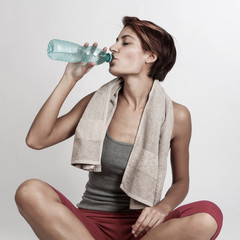 bella ragazza sportiva con il caschetto beve acqua dalla bottiglia dopo aver fatto sport, isolata...