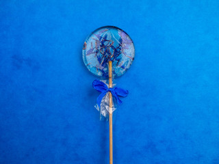 Round lollipop with blue cornflower on trendy blue classic background, flat lay minimal concept, trendy pop art style photo, isolated