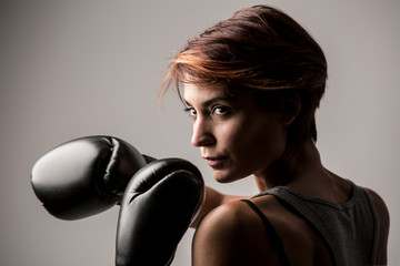Ritratto donna boxer con i guantoni da boxe isolata su sfondo grigio chiaro