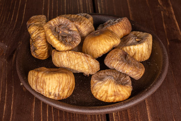 Lot of whole dried fig with brown ceramic coaster on brown wood