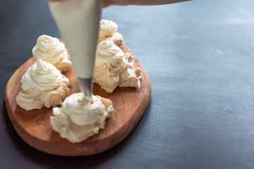 the process of creating Pavlova dessert, decorating the meringue with cream from the culinary bag