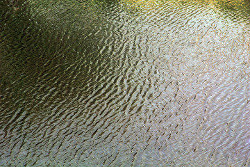 Water with small waves and raindrops on a pool