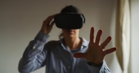 An young happy woman is using innovative technology vr glasses for play games and relax herself after hard working day. Concept of future, innovation, technology, gaming,lifestyle, entertainment