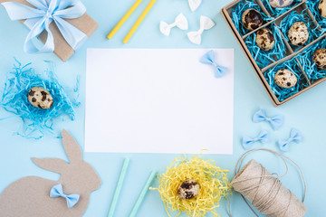 Easter eggs in a paper box and nests. Easter Bunny with a blue bow. Easter gift with a blue ribbon. Blank for a greeting card. Blue background creative.
