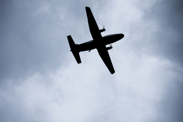 Silhouette two engine propeller airplane on sky, photoshoot from under while plane flying.