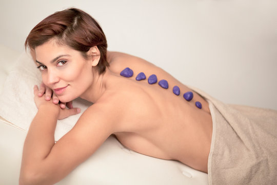 Giovane ragazza si fa massaggiare con le pietre blu sulla schiena