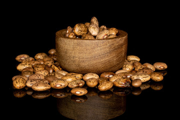 Lot of whole mottled brown bean pinto in bamboo bowl isolated on black glass