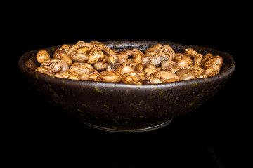Obraz premium Lot of whole mottled brown bean pinto in glazed bowl isolated on black glass