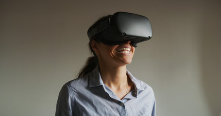 An young happy woman is using innovative technology vr glasses for play games and relax herself after hard working day. Concept of future, innovation, technology, gaming,lifestyle, entertainment