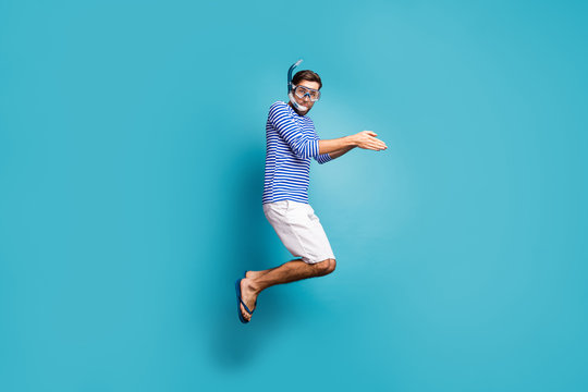 Full length profile photo of funky crazy guy tourist jump high swimming water mask tube diving wear striped sailor shirt vest shorts flip flops isolated blue color background