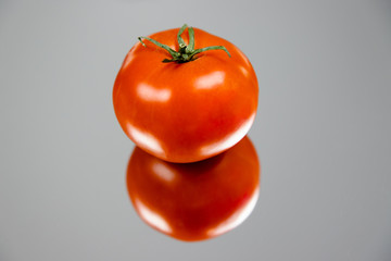 Soczysty pomidor na stole z efektem odbicia