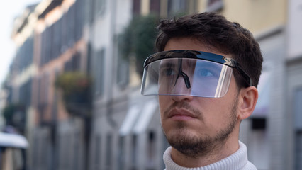 Portrait of an young man is using futuristic innovative technology vr mask in a city center. Concept of future,innovation, immersive technology, gaming,virtual reality