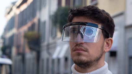 An young man is using futuristic innovative technology vr mask with augmented reality anonymous holograms in a city center. Concept of future,innovation, immersive technology, gaming,virtual reality