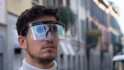 An young man is using futuristic innovative technology vr mask with augmented reality anonymous holograms in a city center. Concept of future,innovation, immersive technology, gaming,virtual reality