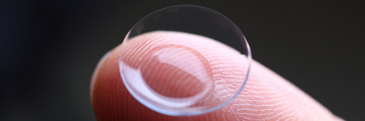 Human finger holding soft contact lens