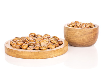 Lot of whole mottled brown bean pinto on round bamboo coaster in bamboo bowl isolated on white background