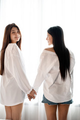 Two women holding hand each other with sweet emotion,beside window,feeling loved,romantic love couple,good friendship,blurry light around