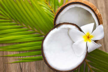 Close-up. Still life of coconut, palm leaves, plumeria flower on a wooden background. Copy space Composition Tropical walnut.