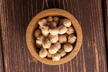 Lot of whole fresh tan chickpea in bamboo bowl flatlay on brown wood