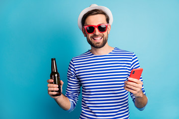 Photo of funky nice traveler guy browsing telephone drink beer bottle all inclusive exotic resort...