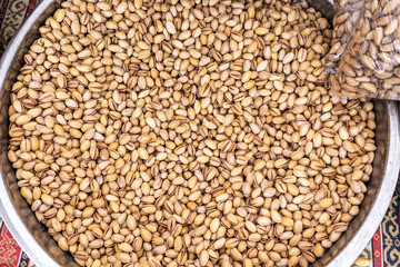Closeup top view of many pistachios nuts isolated in huge bowl selling outdoor in street of city. 