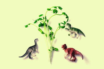 Fresh snow pea sprouts with dinosaurs toys. Healthy diet superfood and micro green eating concept.